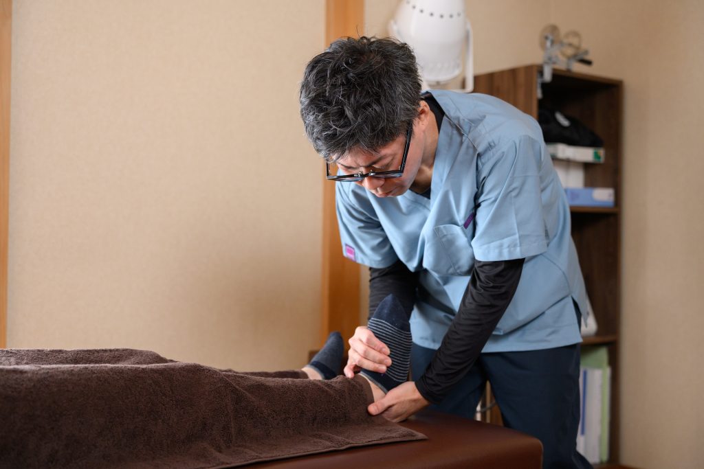 沼津市の接骨院で股関節の痛みのために足首の施術を受ける女性